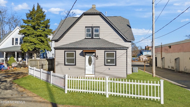 view of front facade featuring a front yard, a fenced front yard, and roof with shingles