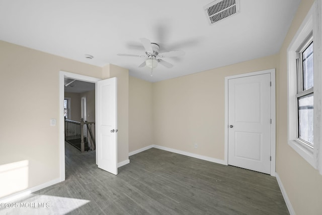 unfurnished bedroom with multiple windows, wood finished floors, visible vents, and baseboards