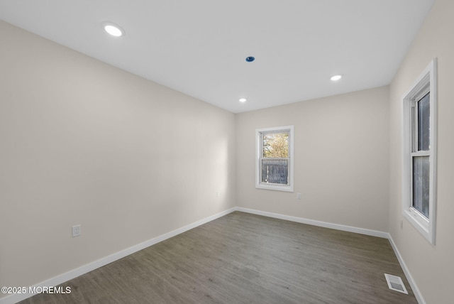 empty room with recessed lighting, wood finished floors, visible vents, and baseboards