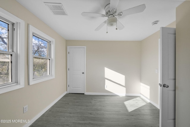 empty room featuring visible vents, baseboards, dark wood finished floors, and a ceiling fan