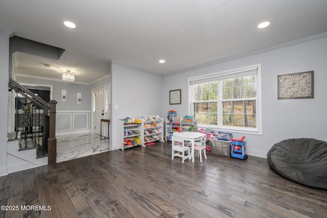 recreation room featuring recessed lighting, a decorative wall, wood finished floors, and ornamental molding