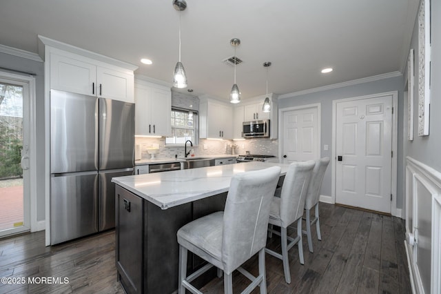 kitchen with backsplash, ornamental molding, stainless steel appliances, and a sink