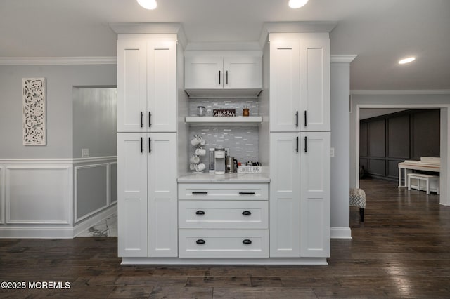 bar with backsplash, a dry bar, ornamental molding, dark wood-style floors, and a decorative wall