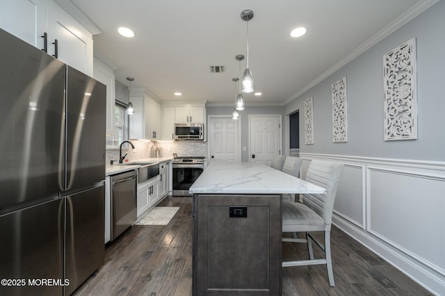 kitchen featuring a breakfast bar area, visible vents, a kitchen island, a sink, and stainless steel appliances