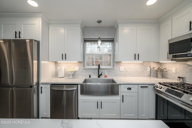 kitchen with light stone counters, white cabinets, stainless steel appliances, and a sink