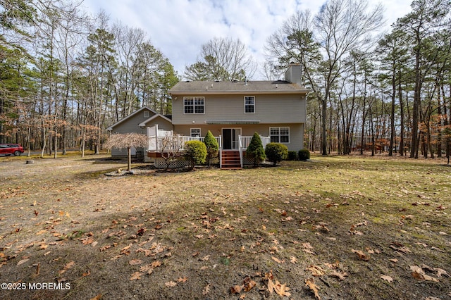 rear view of house featuring a deck, a yard, and a chimney