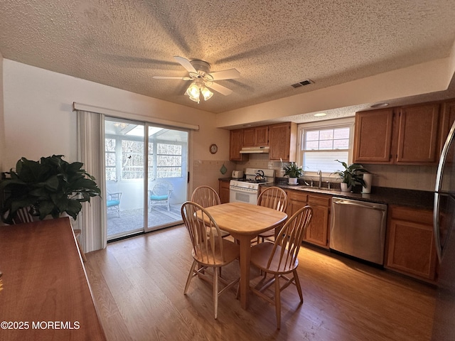 dining space with visible vents, a textured ceiling, light wood-type flooring, and a ceiling fan