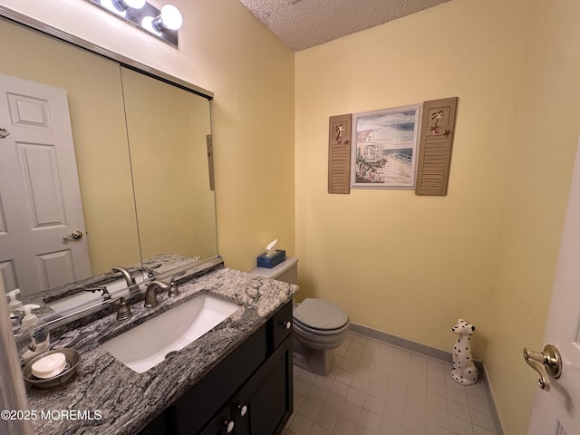 bathroom with baseboards, toilet, vanity, tile patterned floors, and a textured ceiling