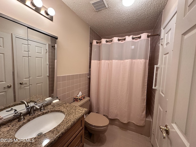 bathroom with visible vents, tile walls, toilet, shower / tub combo, and a textured ceiling