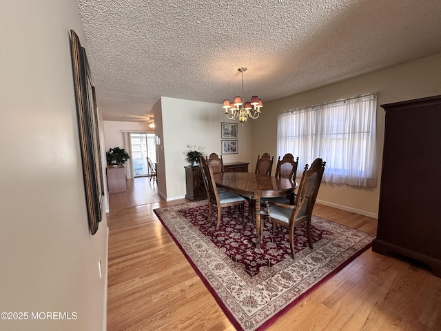 dining room with light wood-style flooring, baseboards, and a textured ceiling