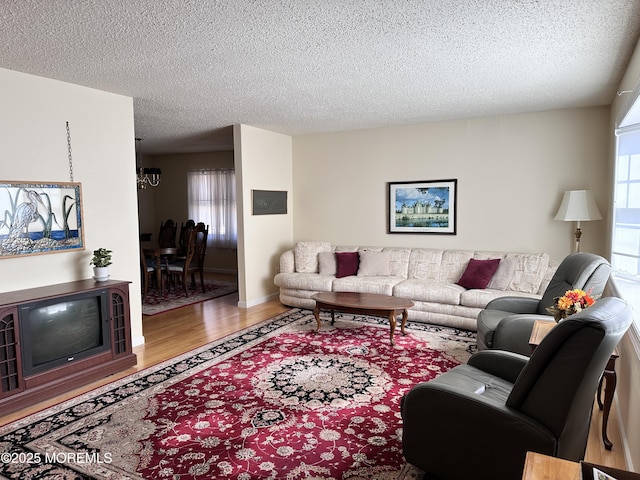 living area with a textured ceiling, wood finished floors, baseboards, and a healthy amount of sunlight