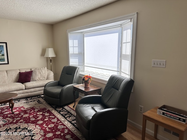 living room with a textured ceiling, baseboards, and wood finished floors