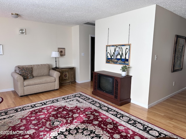 living room featuring visible vents, a textured ceiling, and wood finished floors