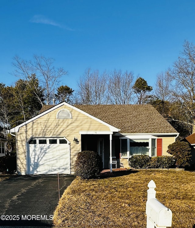 view of front of house featuring a front yard, an attached garage, driveway, and roof with shingles