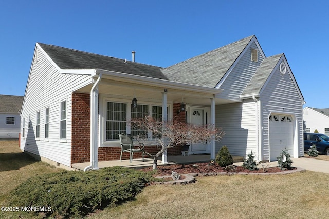 view of front of home featuring driveway, a porch, a front yard, a garage, and brick siding