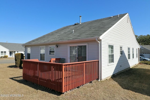 back of house featuring a deck, a yard, and roof with shingles