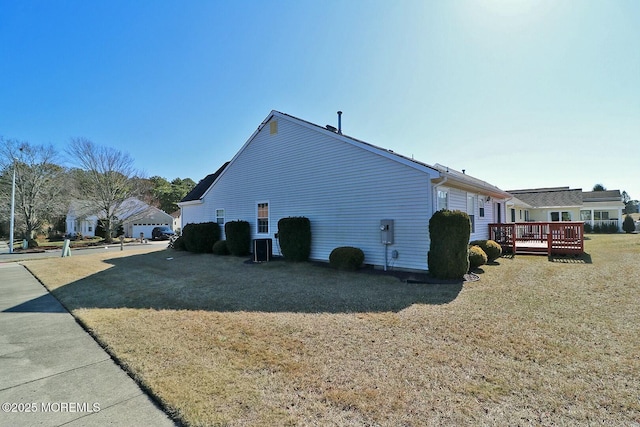 view of side of home featuring a wooden deck, a yard, and central AC unit