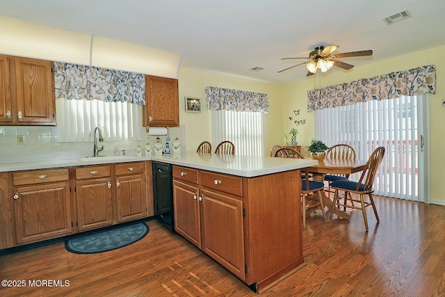 kitchen with visible vents, brown cabinets, a peninsula, and a sink