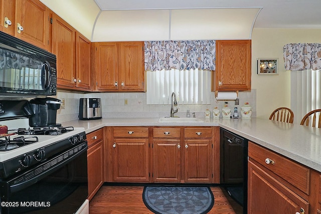 kitchen featuring a sink, black appliances, brown cabinetry, and light countertops