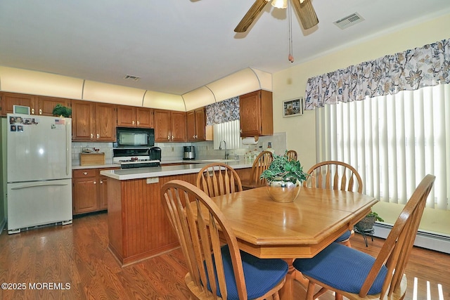 kitchen with visible vents, dark wood finished floors, light countertops, brown cabinetry, and white appliances