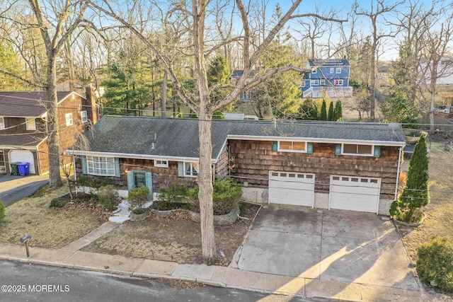 view of front facade with an attached garage, concrete driveway, and a shingled roof