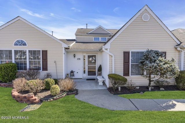 traditional home featuring roof with shingles and a front lawn