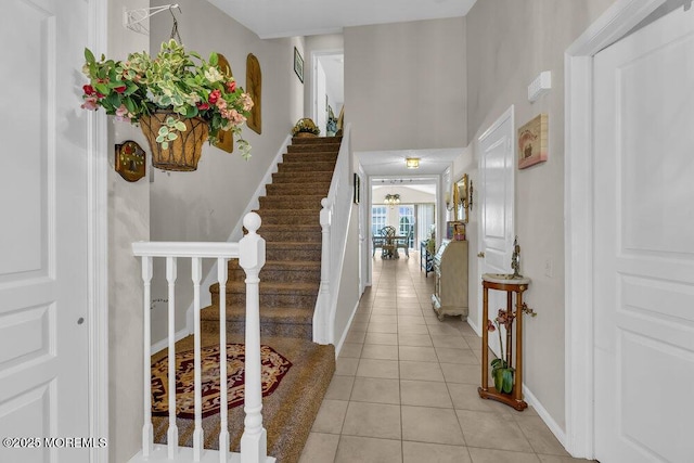 foyer with stairway, light tile patterned floors, and baseboards