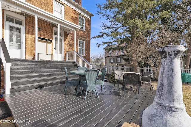 wooden terrace with outdoor dining space and fence