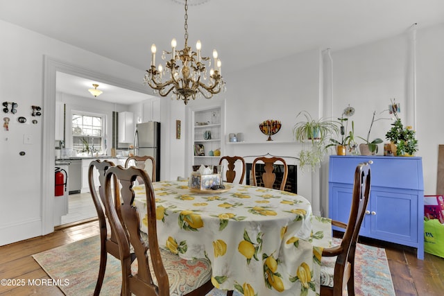 dining room featuring built in features, dark wood-style flooring, and a chandelier