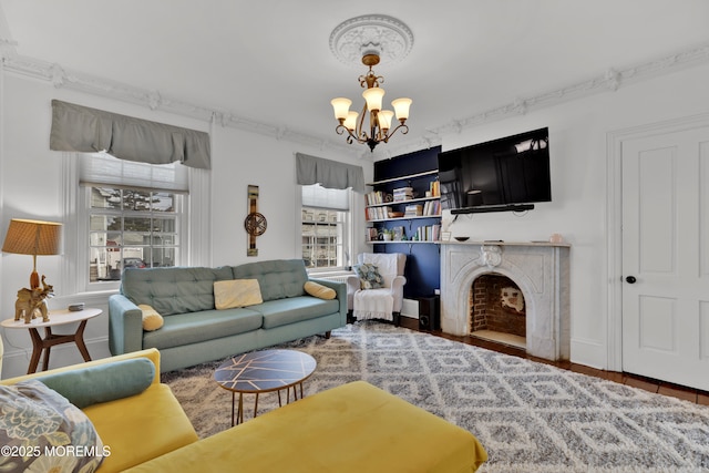 living area with baseboards, wood finished floors, a chandelier, and a fireplace