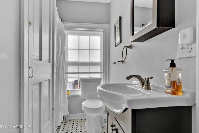 bathroom with toilet, vanity, and baseboards