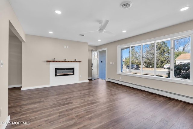 unfurnished living room with visible vents, a glass covered fireplace, dark wood-style floors, recessed lighting, and a baseboard radiator