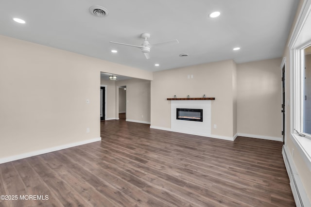 unfurnished living room with wood finished floors, visible vents, recessed lighting, a glass covered fireplace, and baseboard heating