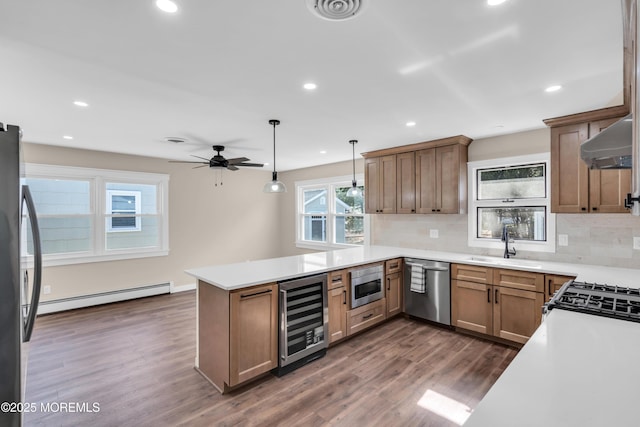 kitchen featuring range hood, beverage cooler, a baseboard radiator, a peninsula, and appliances with stainless steel finishes