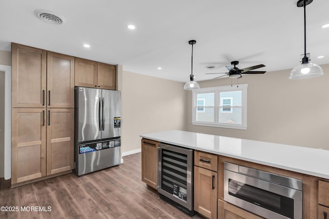 kitchen with visible vents, beverage cooler, decorative light fixtures, wood finished floors, and appliances with stainless steel finishes