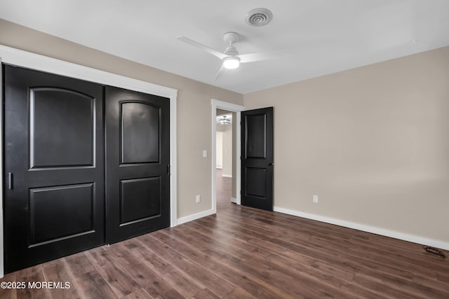 unfurnished bedroom with baseboards, visible vents, ceiling fan, dark wood-type flooring, and a closet