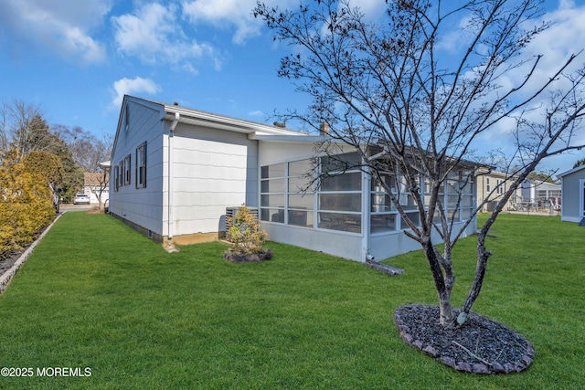 rear view of property with a lawn and a sunroom