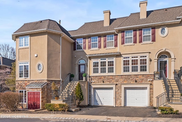 townhome / multi-family property featuring stairs, aphalt driveway, stone siding, and stucco siding