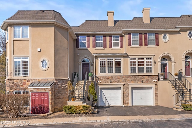 view of property featuring stucco siding, stone siding, driveway, and stairway