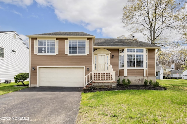 split level home with an attached garage, aphalt driveway, and a front lawn