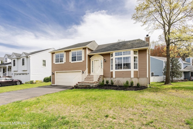 split level home with a front yard, an attached garage, a chimney, and aphalt driveway