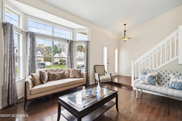 living area with lofted ceiling, wood finished floors, stairs, and baseboards