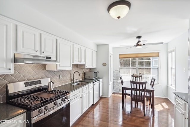 kitchen with white cabinets, dark countertops, under cabinet range hood, and appliances with stainless steel finishes