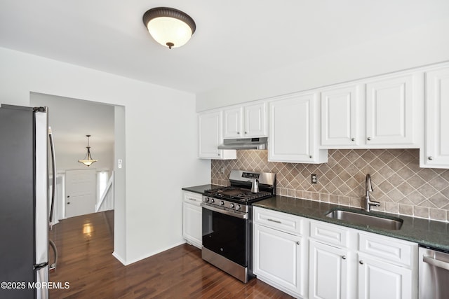 kitchen featuring under cabinet range hood, a sink, dark wood-type flooring, decorative backsplash, and appliances with stainless steel finishes