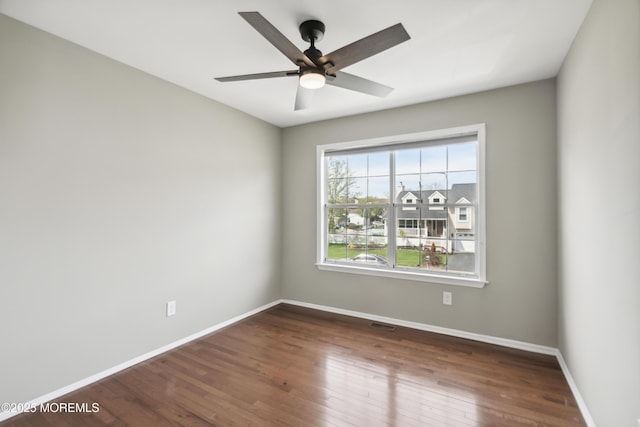 unfurnished room with dark wood finished floors, visible vents, baseboards, and ceiling fan