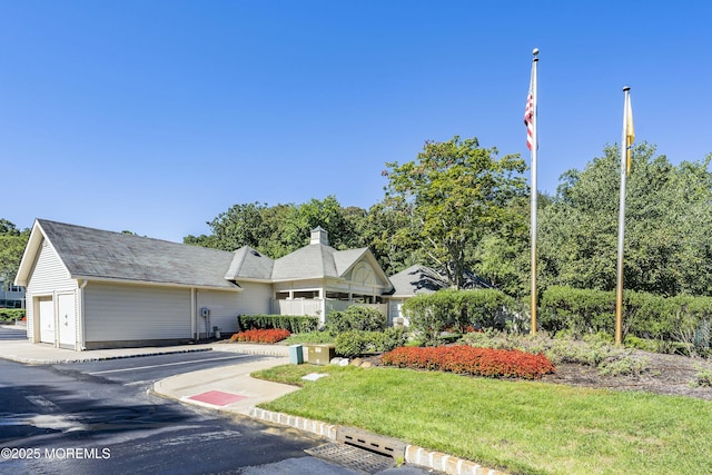 view of front facade featuring a front lawn, a chimney, and a garage