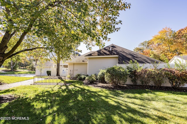 view of front of home featuring a front lawn, fence, and a shingled roof