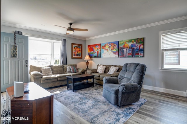 living area with baseboards, wood finished floors, ornamental molding, and a ceiling fan