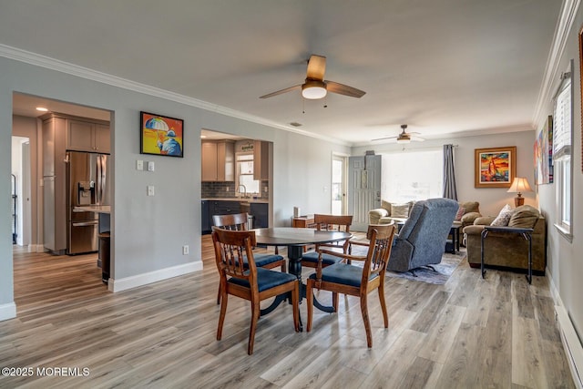 dining space with a ceiling fan, baseboards, light wood-style floors, and crown molding