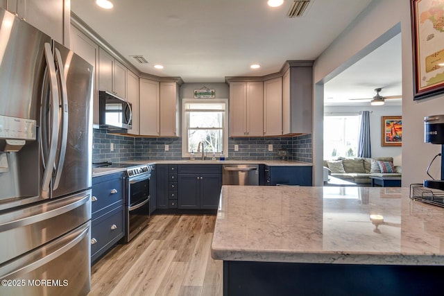 kitchen featuring visible vents, a sink, gray cabinetry, light wood-style floors, and appliances with stainless steel finishes